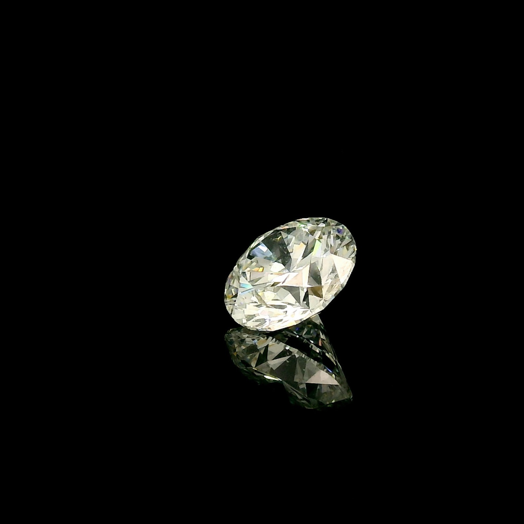 A 1.5 ct. Round Cut Lab Grown Diamond resting on a black surface with its reflection visible below.