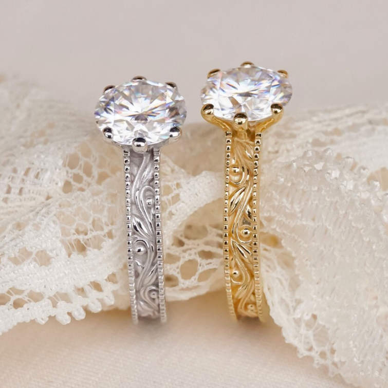 Two diamond rings, one gold and one silver, on a lace fabric background.