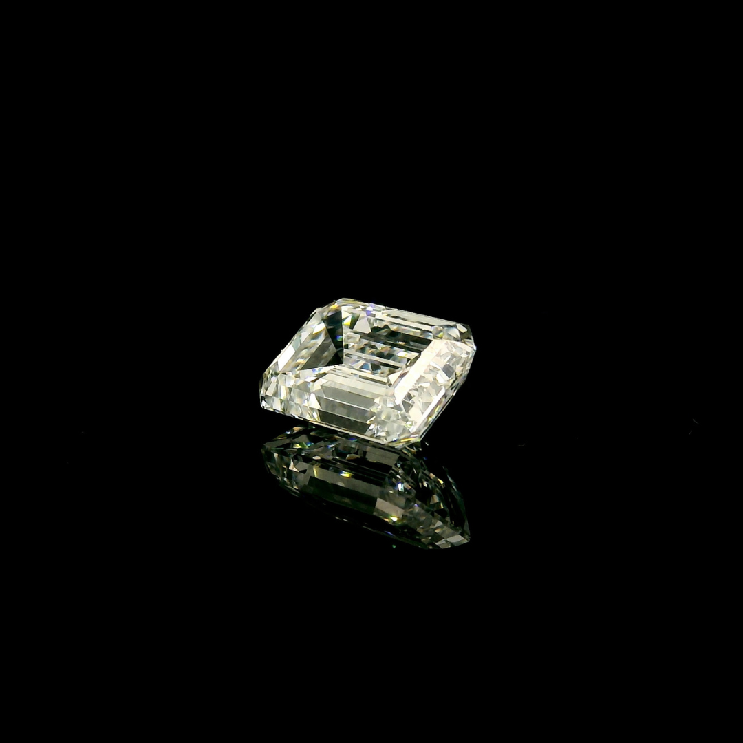 A 2 ct. Emerald Cut Lab Grown Diamond reflecting on a black surface.