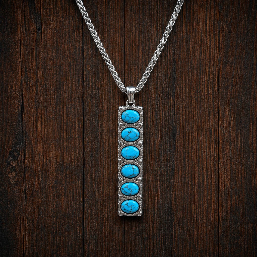 Introducing The Clara: a striking Western necklace featuring a vertical rectangular silver pendant set with six round turquoise stones, evoking the timeless appeal of classic Western jewelry and beautifully displayed on a dark wooden background.