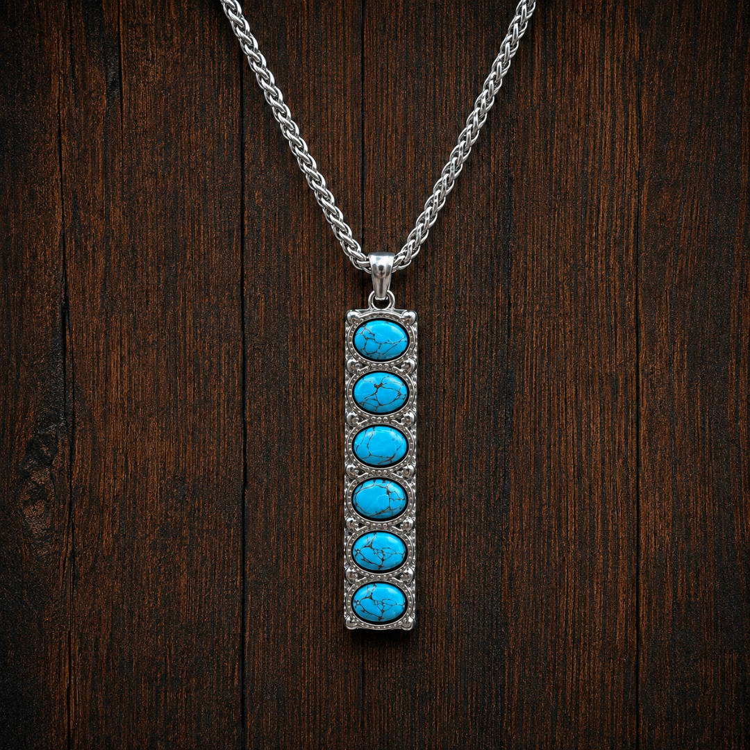 Introducing The Clara: a striking Western necklace featuring a vertical rectangular silver pendant set with six round turquoise stones, evoking the timeless appeal of classic Western jewelry and beautifully displayed on a dark wooden background.
