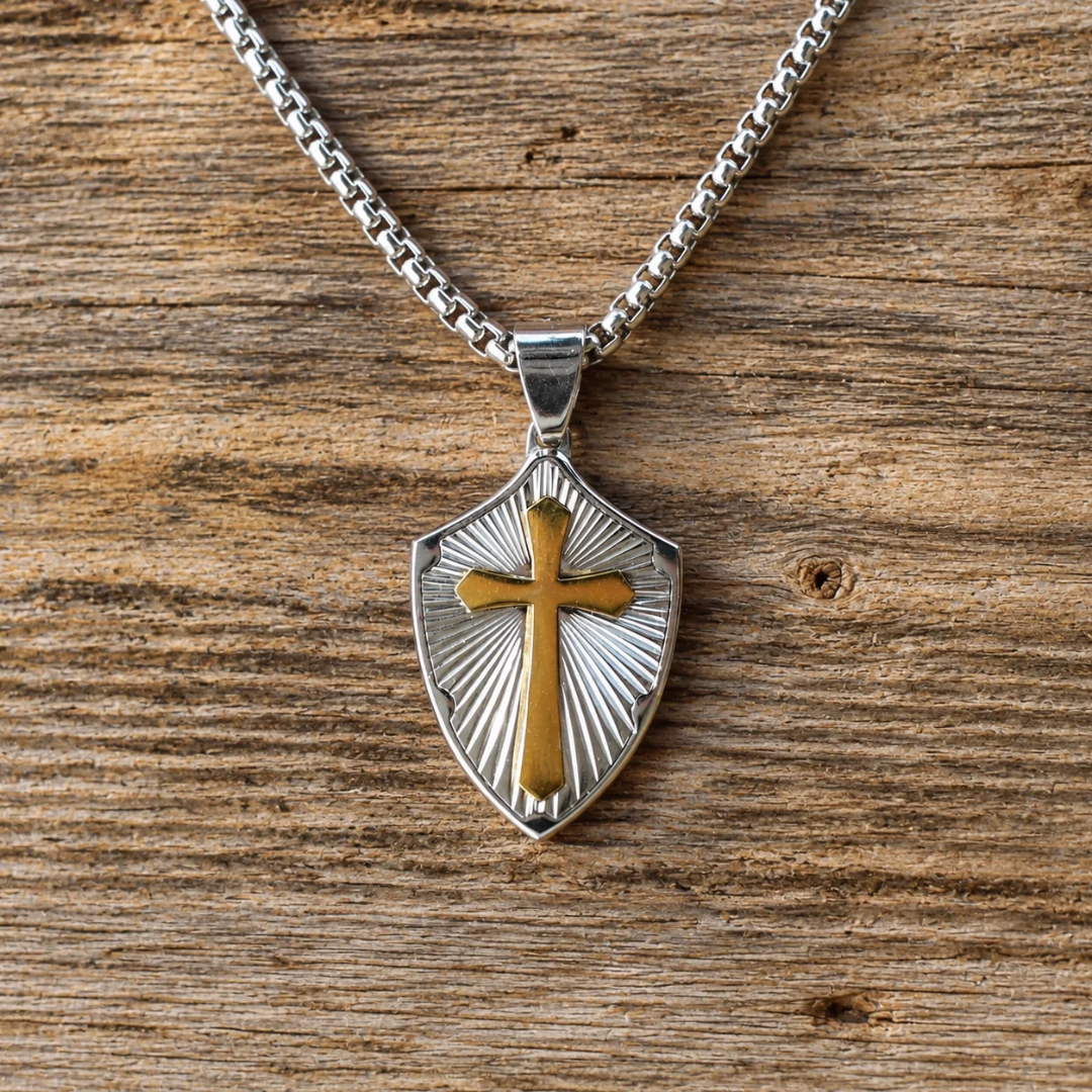 The David is a silver-tone box chain necklace with a shield-shaped cross pendant featuring a gold-tone overlay.