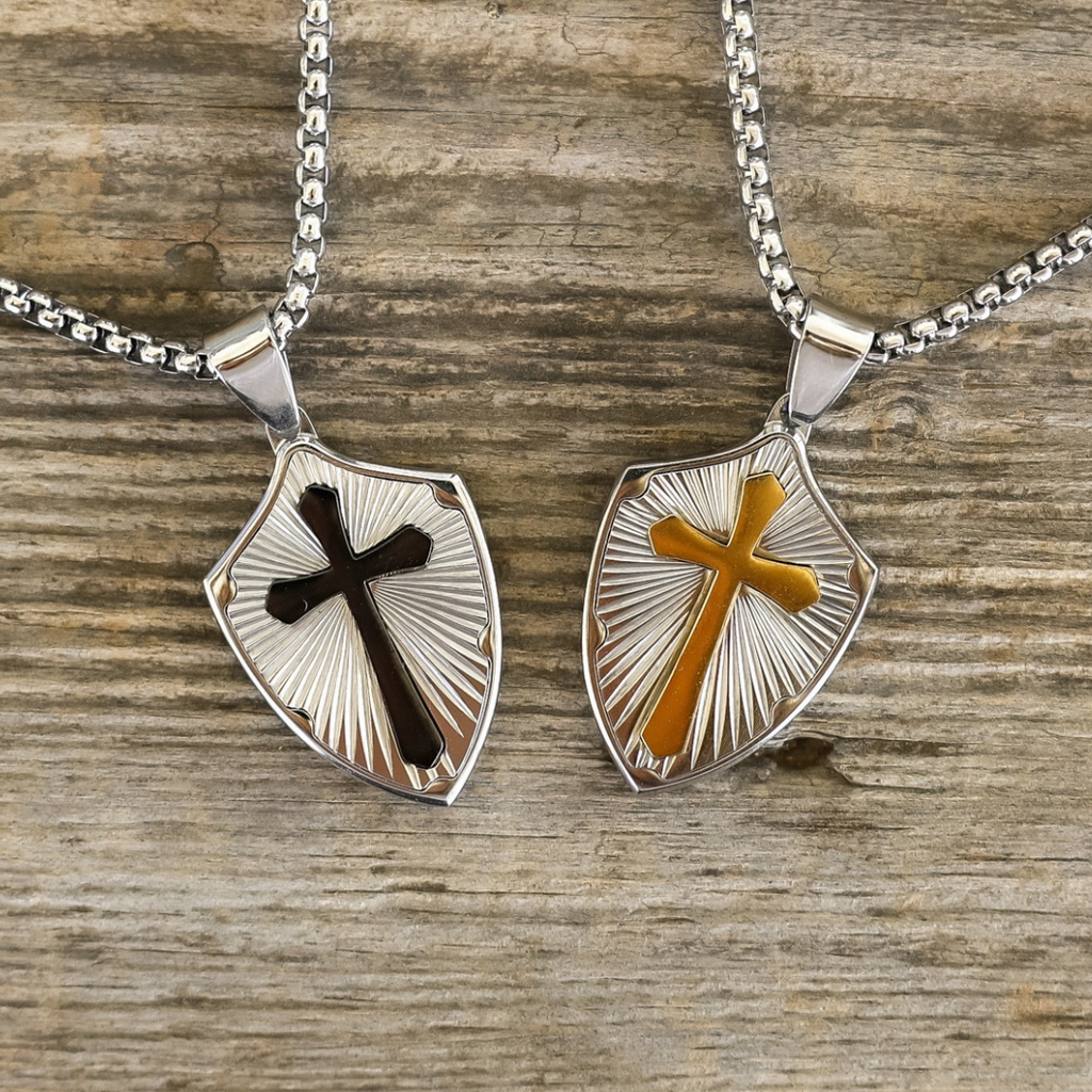 The David necklace features two shield pendants on silver-tone chains: one with a black cross and the other with a gold-tone cross, each set against a sunburst background.