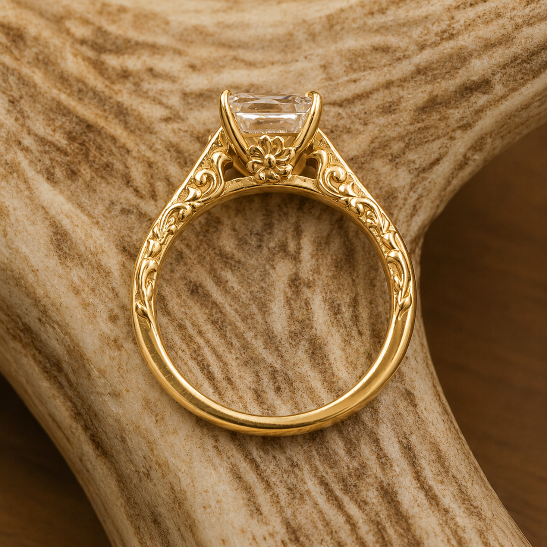The Diamond Emory ring, featuring intricate floral engravings and a large central gemstone inspired by Western motifs, rests on a textured, light-colored antler.