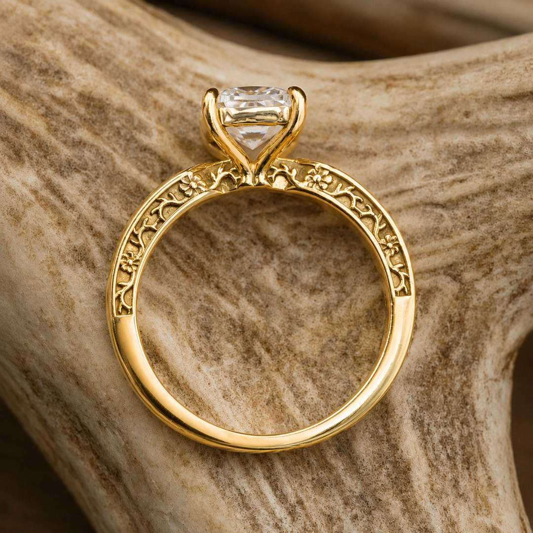 The Diamond Rochelle ring, featuring floral engravings and a large, clear lab-grown diamond, is displayed resting on a textured, light brown surface.