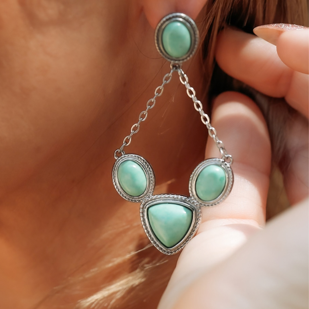The Eve Drop Earrings featuring four light green stones set in silver metal frames.