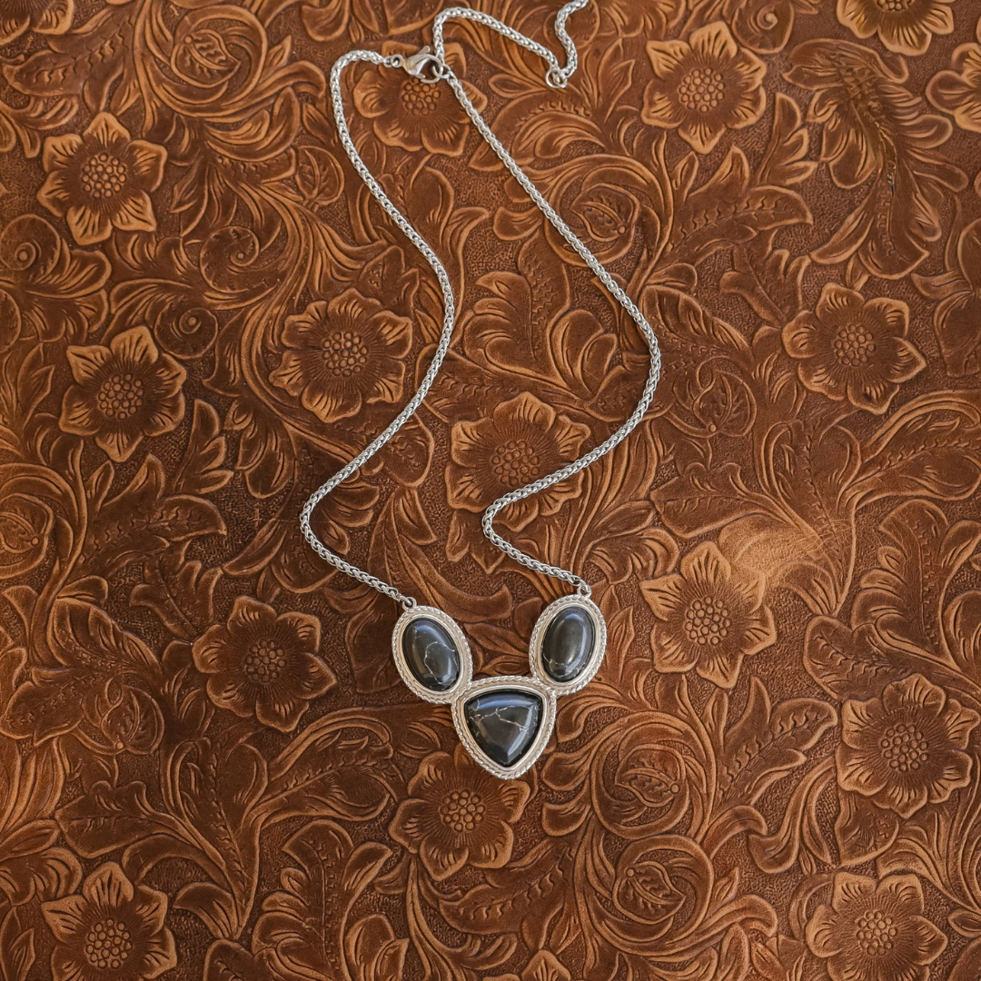 The Eve silver rope chain necklace featuring three dark, rounded stone pendants in a Western style.