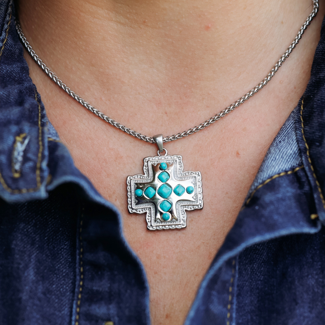 The Kalyn—a silver chain necklace with a cross-shaped pendant adorned with turquoise stones—exudes classic Western jewelry style and looks striking paired with a denim shirt.