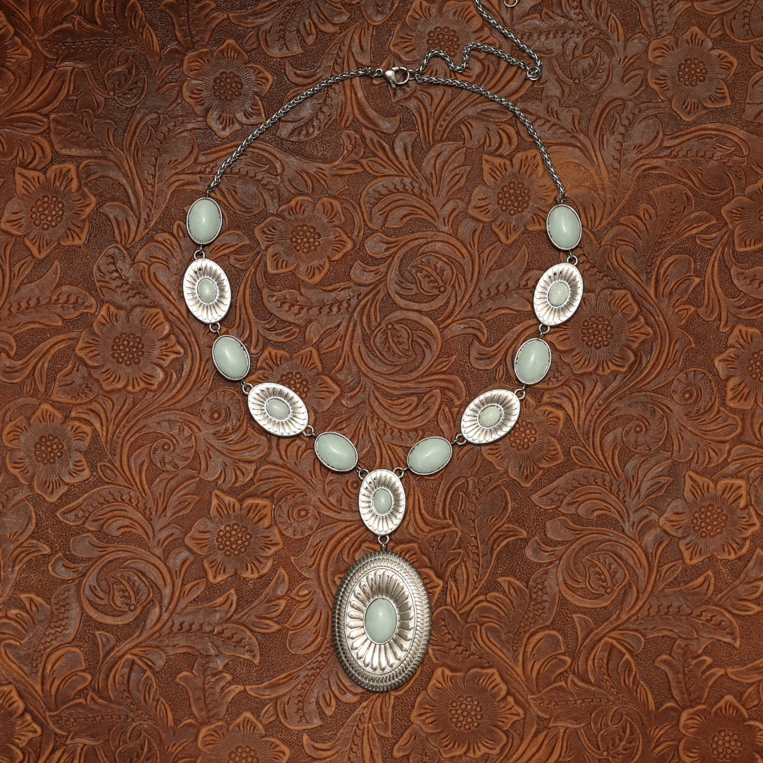 The Kathryn is a Western-style statement necklace with silver-toned oval settings holding pale green stones, featuring a large oval pendant at the center.