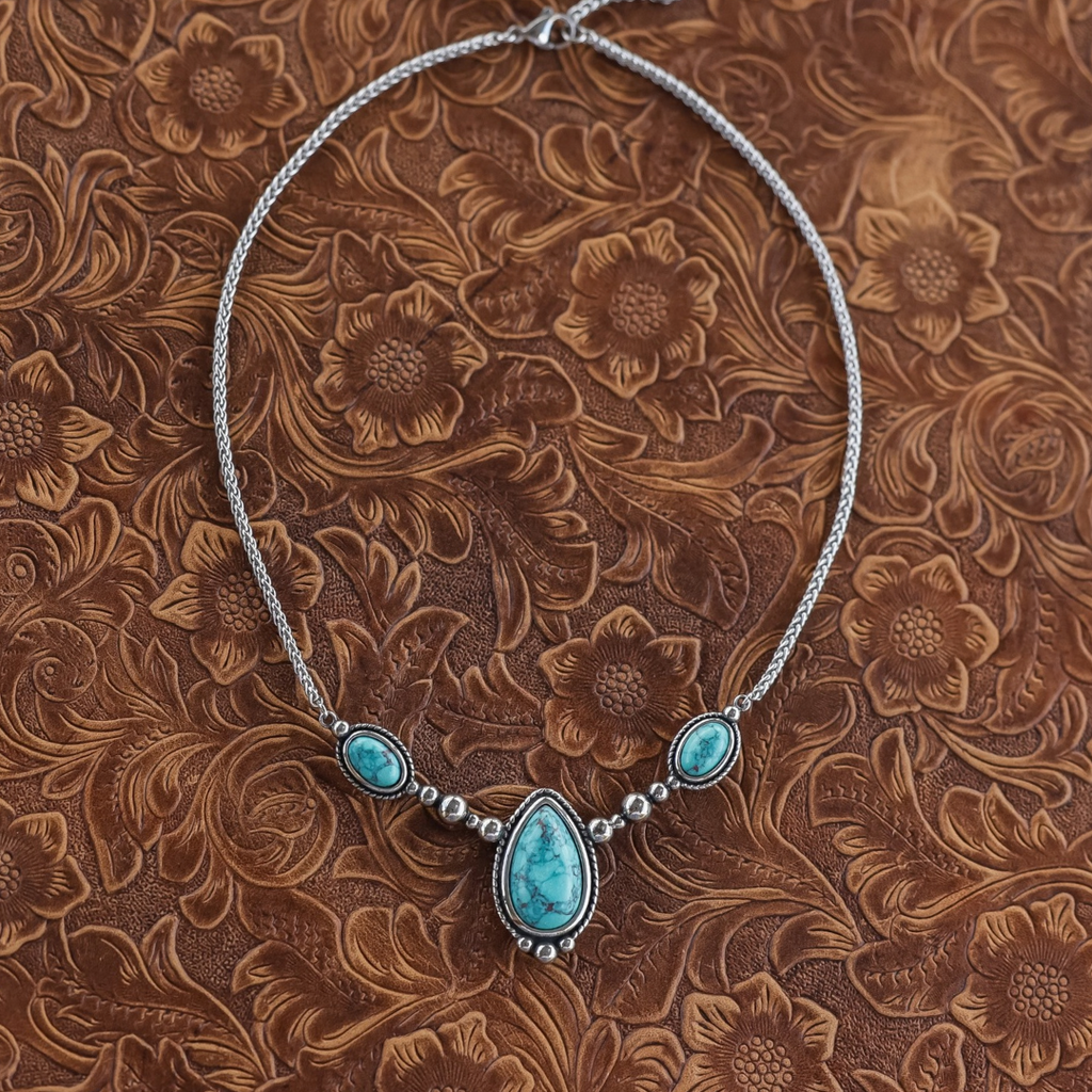 The Kay silver Western necklace features a central teardrop-shaped turquoise stone flanked by two smaller oval turquoise stones on a woven chain.