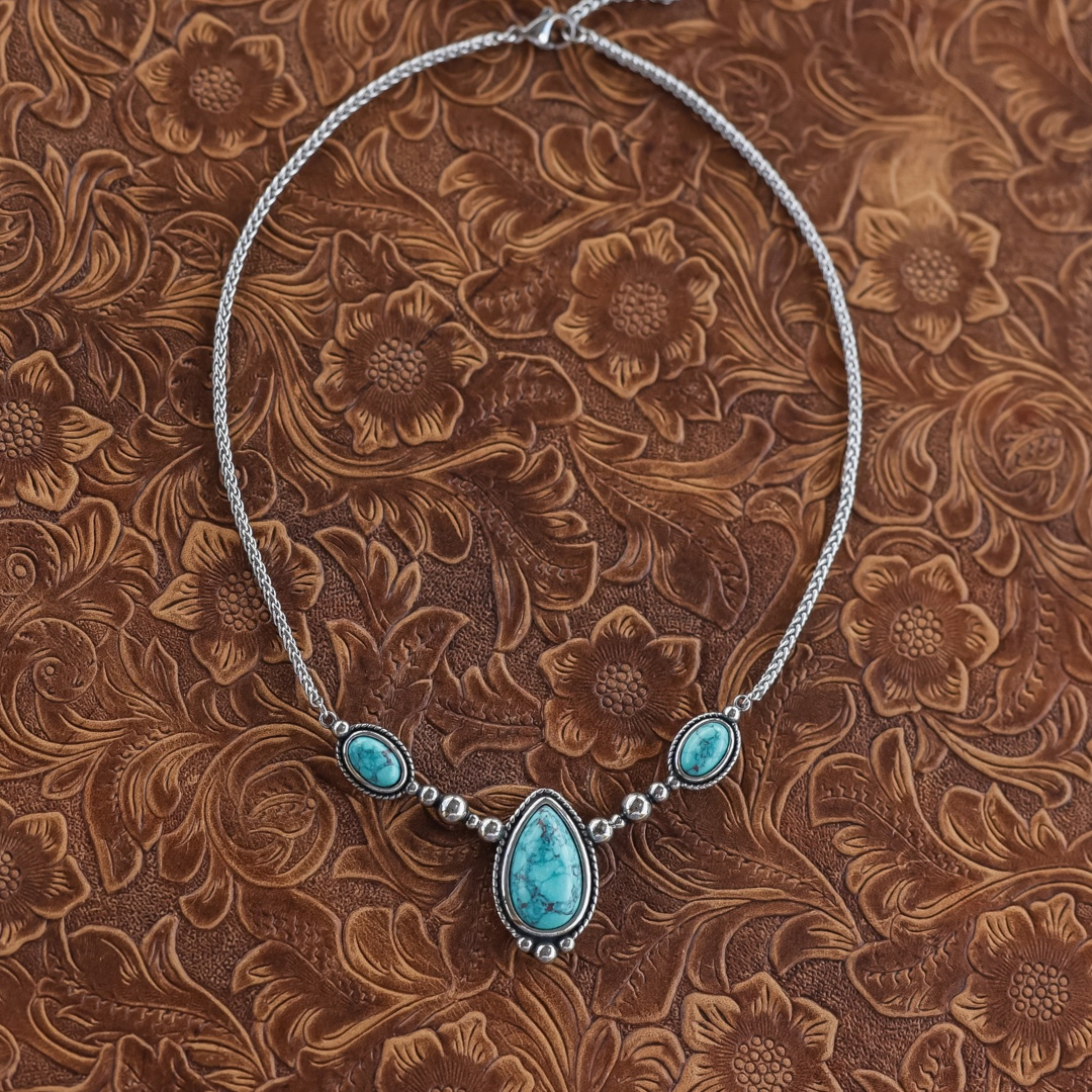 The Kay silver Western necklace features a central teardrop-shaped turquoise stone flanked by two smaller oval turquoise stones on a woven chain.