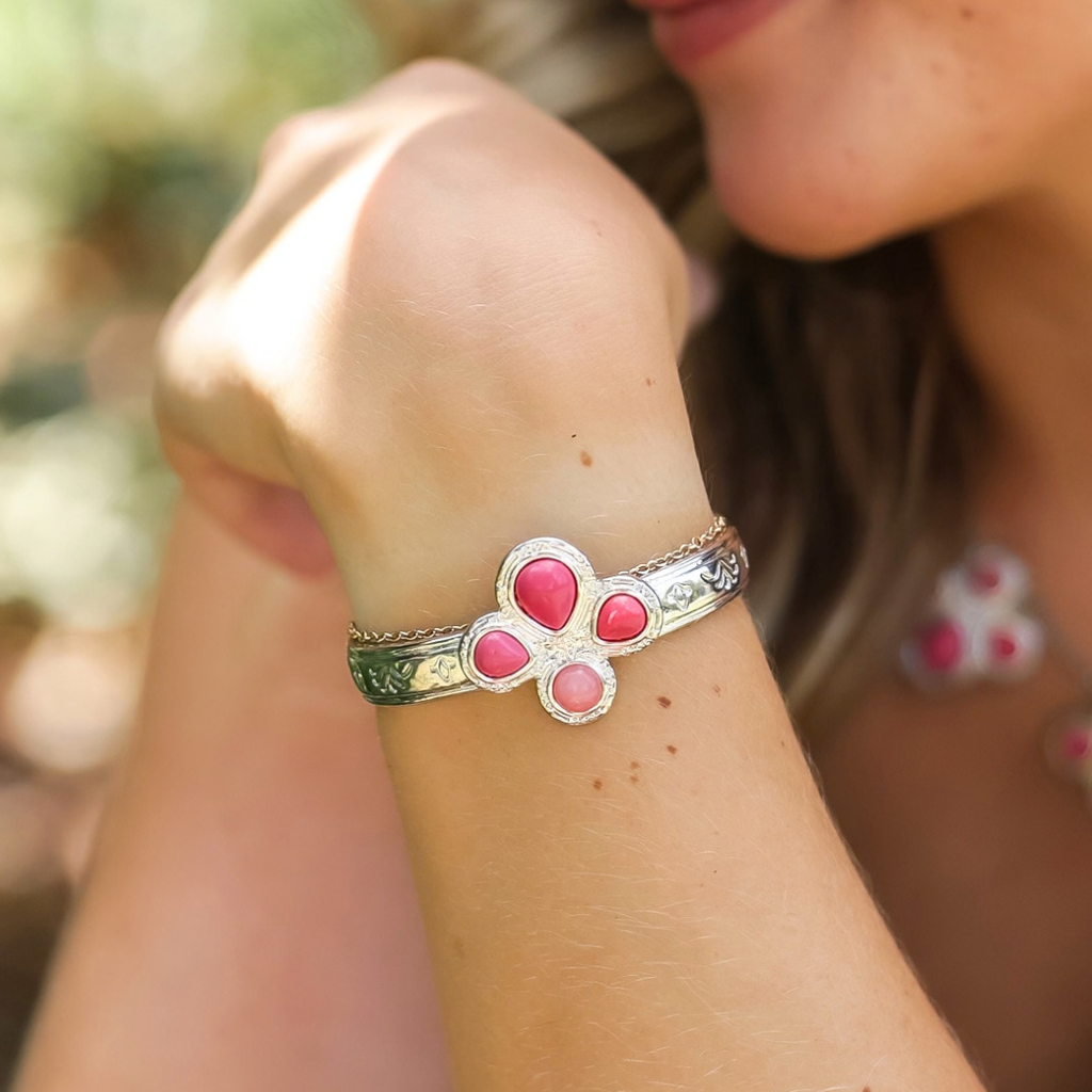 A person wears a silver The Prairie Rose Cuff featuring a pink, flower-shaped inlay.